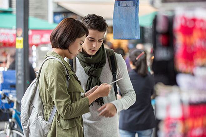 Foreign tourists looking at the tour guidebook to find their way.